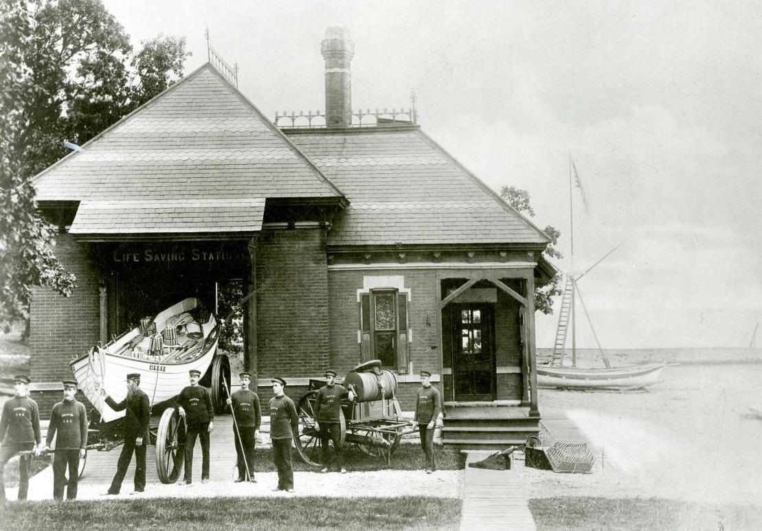 Period photograph of the Parkinson-designed 1877 station building, with the station’s Beebe type pulling surfboat on its boat wagon at left, and the beach cart at center. Keeper Lawson can be seen at the front of the surfboat. (Courtesy of NWU Deering Library) Period photograph of the Parkinson-designed 1877 station building, with the station’s Beebe type pulling surfboat on its boat wagon at left, and the beach cart at center. Keeper Lawson can be seen at the front of the surfboat. (Courtesy of NWU Deering Library)